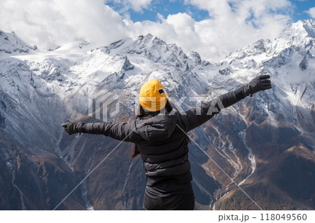 Rear view of female tourist raised her hands after reached to top of Tsergo Ri (4,990m) the high point on the Langtang valley trek of Nepal. Rear view of female tourist raised her hands after reached to top of Tsergo Ri (4,990m) the high point on the Langtang valley trek of Nepal. 118049560