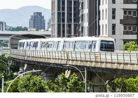 View of a Wenhu or Brown line train running on the elevated track of the Taipei Mass Rapid Transit System with the building background. View of a Wenhu or Brown line train running on the elevated track of the Taipei Mass Rapid Transit System with the building background. 118050807