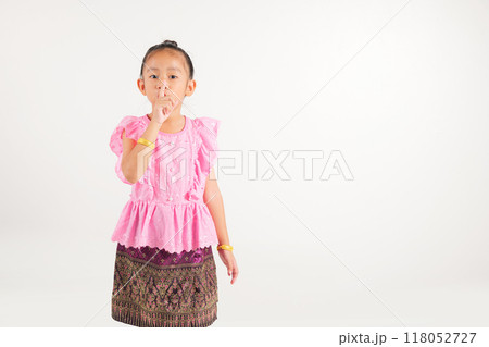Portrait Thailand kid girl smiling traditional Thai dress costume making finger on lips mouth silent quiet gesture, studio isolated white background, kindergarten child marking silence for stop quiet Portrait Thailand kid girl smiling traditional Thai dress costume making finger on lips mouth silent quiet gesture, studio isolated white background, kindergarten child marking silence for stop quiet 118052727