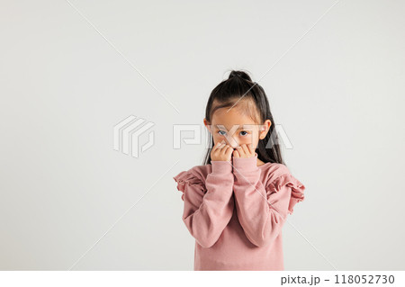 Asian portrait cute young kid girl standing amazed, shocked afraid mouth covered gesturing hand palms looking camera, studio shot isolated on white background, Thai kindergarten child scared Asian portrait cute young kid girl standing amazed, shocked afraid mouth covered gesturing hand palms looking camera, studio shot isolated on white background, Thai kindergarten child scared 118052730