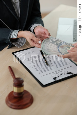 A woman is handing a stack of money to a man 118052964