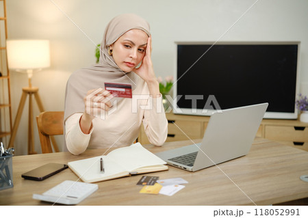 A woman is sitting at a desk with a laptop and a stack of credit cards 118052991