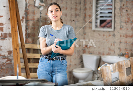 Woman making notes on indoor construction site Woman making notes on indoor construction site 118054010