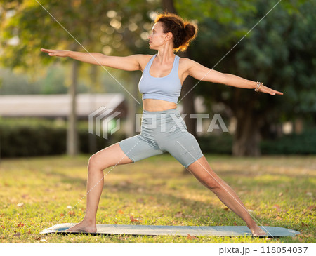 Adult woman doing yoga in warrior pose 118054037