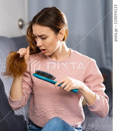 Upset girl shocked by the fallen hair on comb 118054113