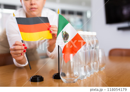 Employee of delegation prepares negotiating table - sets up flag of Mexico and Germany Employee of delegation prepares negotiating table - sets up flag of Mexico and Germany 118054179