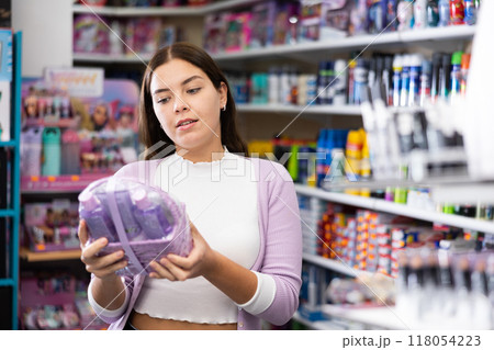 Young girl buying set of skin and haircare products in beauty boutique Young girl buying set of skin and haircare products in beauty boutique 118054223
