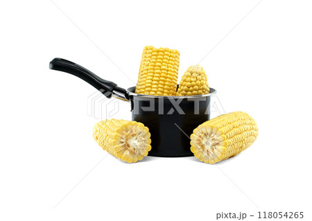 Fresh corn cobs in a black saucepan and scattered around against a white background 118054265