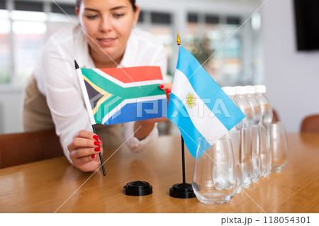 Preparing for business presentation - secretary places flags of Argentina and South Africa on negotiating table Preparing for business presentation - secretary places flags of Argentina and South Africa on negotiating table 118054301
