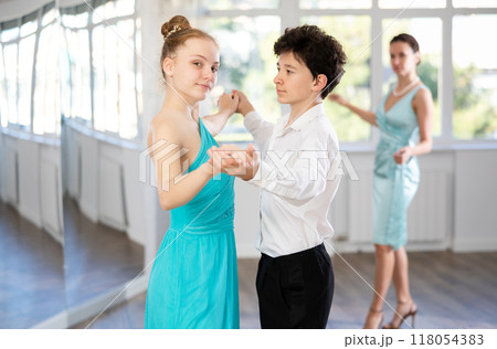 Adolescent dance duo, boy and girl, refining slow foxtrot with female coach Adolescent dance duo, boy and girl, refining slow foxtrot with female coach 118054383