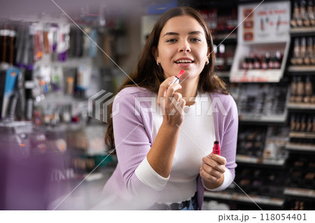 Girl is searching for reliable lipstick in cosmetics shop Girl is searching for reliable lipstick in cosmetics shop 118054401