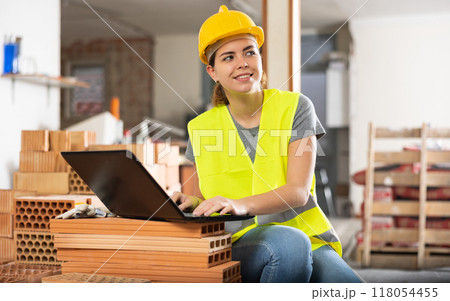 Woman with laptop on indoor construction site Woman with laptop on indoor construction site 118054455