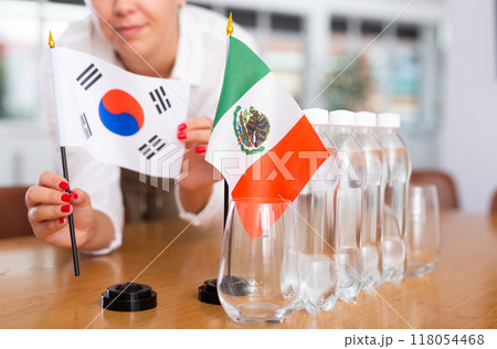 Woman secretary prepares an office for negotiations - she places flags of South Korea and Mexico table Woman secretary prepares an office for negotiations - she places flags of South Korea and Mexico table 118054468
