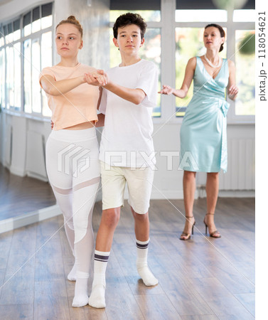 Couple of teenage dancers rehearsing ballroom dance with female teacher 118054621
