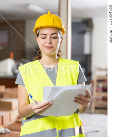 Female architect taking notes in building under renovation Female architect taking notes in building under renovation 118054659
