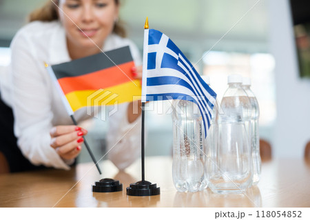 Unrecognizable girl sets midget flags of Greece and Germany before international negotiations Unrecognizable girl sets midget flags of Greece and Germany before international negotiations 118054852
