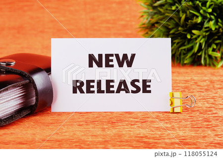 Text NEW RELEASE on a white card on an orange background, close-up, front view 118055124