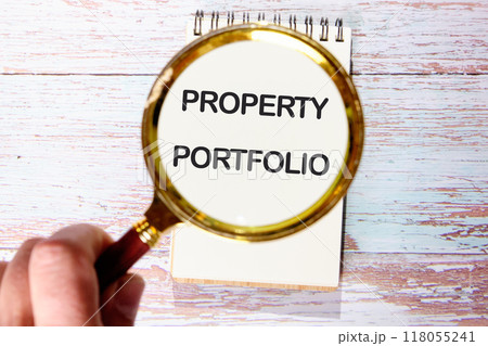 Business Property portfolio concept. Copy space. Symbol. Concept words Property portfolio on a blank sheet of notepad through a magnifying glass 118055241