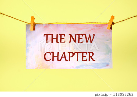 Conceptual the new chapter symbol. Copy space. The new chapter words written on a piece of paper in a clothespin on a rope on a yellow background Conceptual the new chapter symbol. Copy space. The new chapter words written on a piece of paper in a clothespin on a rope on a yellow background 118055262