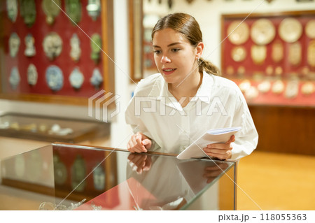 Woman looking at exhibits in glazed stands in museum 118055363