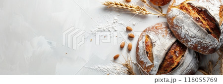 A freshly baked wheat bread loaf sits on a white background with wheat stalks and almonds. Generative AI 118055769
