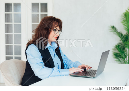 business woman in glasses working on laptop online training in office 118056224