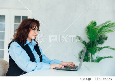 business woman in glasses working on laptop online training in office 118056225