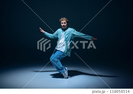 Stylish young guy, hip-hop dancer in motion on stage, training, performing with energy against navy blue background Stylish young guy, hip-hop dancer in motion on stage, training, performing with energy against navy blue background 118058514
