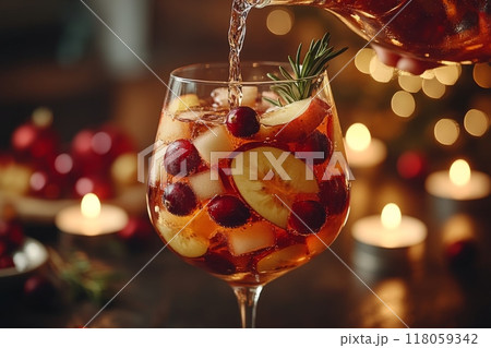 Female Hand Pouring Holiday Sangria in Glasses with Fruit Slice, Cranberry, and Rosemary on Dark Christmas Background 118059342
