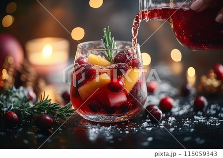 Female Hand Pouring Holiday Sangria in Glasses with Fruit Slice, Cranberry, and Rosemary on Dark Christmas Background 118059343