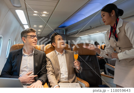 Flight attendant serving orange juice to businessman on plane. Flight attendant serving orange juice to businessman on plane. 118059643