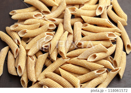 Dry penne pasta with gluten free quinoa ingredients on a wooden surface. Macro shot Dry penne pasta with gluten free quinoa ingredients on a wooden surface. Macro shot 118061572