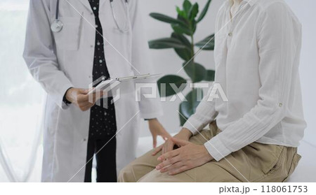 Doctor and a patient discussing something. The female physician, wearing a white medical coat standing with a clipboard during a consultation in the clinic, close up. Medicine concept Doctor and a patient discussing something. The female physician, wearing a white medical coat standing with a clipboard during a consultation in the clinic, close up. Medicine concept 118061753