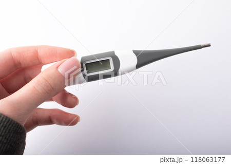 Womans hand holding a digital thermometer. Measuring body temperature. Health check. Health care concept. High quality photo 118063177