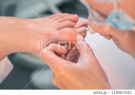 Pedicurist is making hardware pedicure using electricmachine in beauty salon. Pedicurist is making hardware pedicure using electricmachine in beauty salon. 118063582