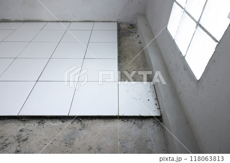Tile floor under construction in room. Tile floor under construction in room. 118063813