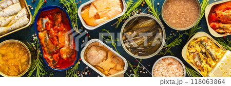 A top view of open tin cans with canned salmon, mackerel, sprat, sardine, tuna, herring, and fish pate, surrounded by spices and herbs on a blue background 118063864