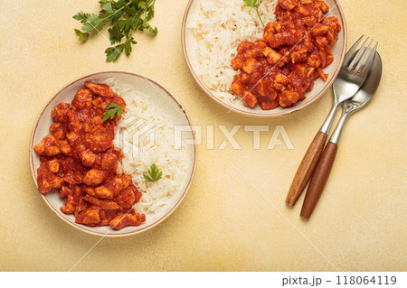 Indian chicken curry served with white rice and turmeric on yellow background top view 118064119