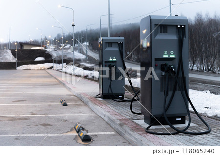 new electric charging station against the backdrop of misty mountains and the road leading to a holiday resort 118065240
