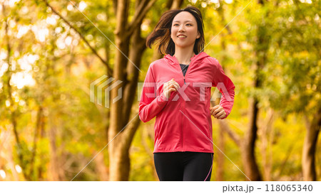 スポーツの秋・紅葉の中でジョギングをする若い女性 118065340