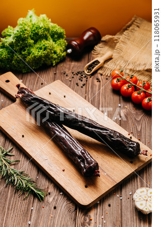 Smoked salami sticks on a wooden board with herbs, perfect for charcuterie boards and gourmet snacks Smoked salami sticks on a wooden board with herbs, perfect for charcuterie boards and gourmet snacks 118065931