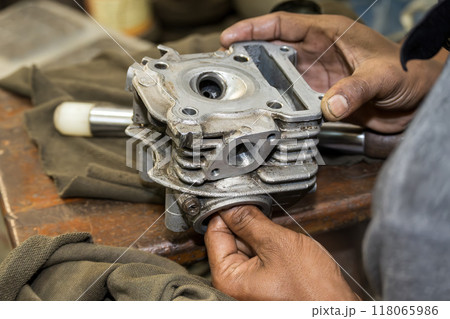 The mechanic man repairing the motorbike engine part. The mechanic man repairing the motorbike engine part. 118065986