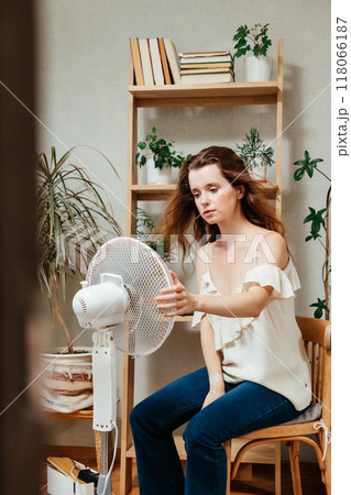 electric fan cools exhausted Caucasian woman languishing in summer heat electric fan cools exhausted Caucasian woman languishing in summer heat 118066187