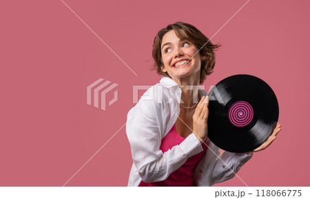 Positive short haired woman with vinyl record disc on pink. Hobby, music lover, collection, nostalgia lifestyle. Copy space. Positive short haired woman with vinyl record disc on pink. Hobby, music lover, collection, nostalgia lifestyle. Copy space. 118066775