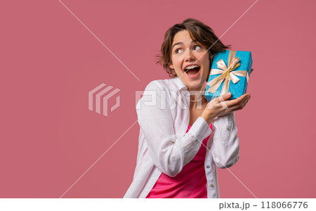 Happy woman with gift box on pink background. Lady smiling, interested what's inside. Copy space. Happy woman with gift box on pink background. Lady smiling, interested what's inside. Copy space. 118066776