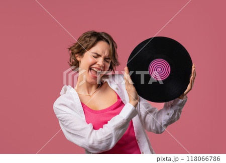 Positive short haired woman with vinyl record disc on pink. Hobby, music lover, collection, nostalgia lifestyle 118066786
