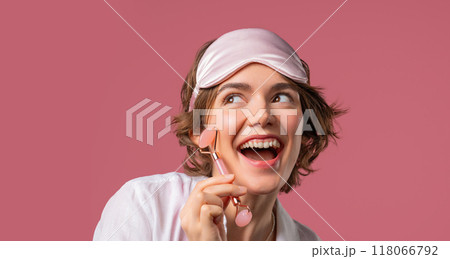 Young woman with rose quartz stone roller on pink background. Facial self care, morning beauty rituals, cosmetology, anti aging and anti-wrinkle treatment Young woman with rose quartz stone roller on pink background. Facial self care, morning beauty rituals, cosmetology, anti aging and anti-wrinkle treatment 118066792