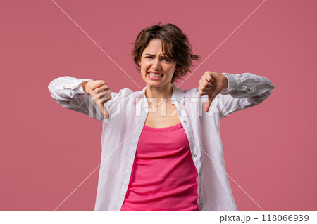 Pretty woman with sign of dislike. Grimacing condemning lady showing thumbs-down Pretty woman with sign of dislike. Grimacing condemning lady showing thumbs-down 118066939