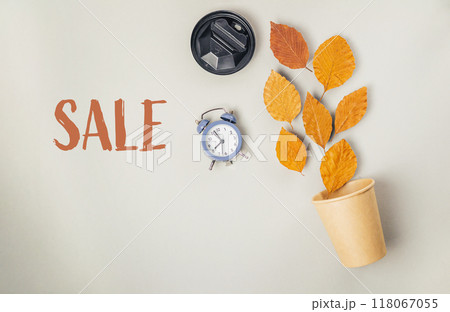 Sale sign with a clock and leaves on a table 118067055