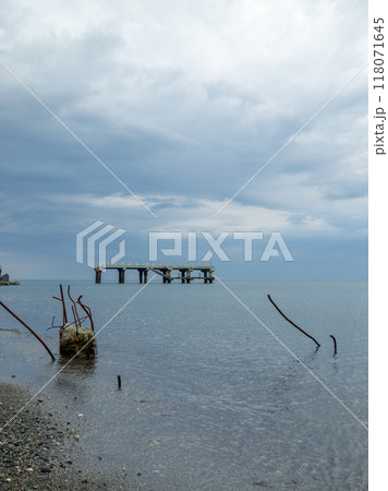 Reinforced concrete sticking out of the water. Remains of an old bridge in the sea. Ruined pier. Abandoned. Armature at sea. 118071645